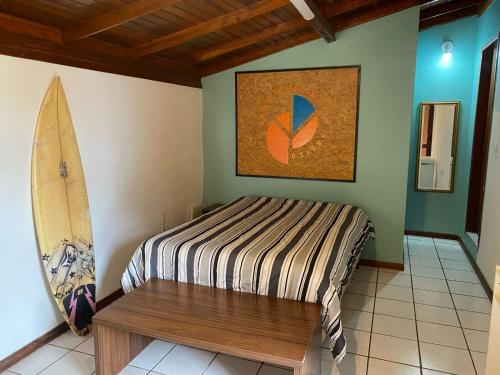 een slaapkamer met een bed en een surfplank aan de muur bij Suíte Quarto Amplo - Sul da Ilha in Florianópolis