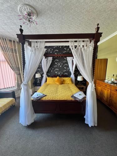 a bedroom with a canopy bed with white curtains at The Holmlea in Blackpool