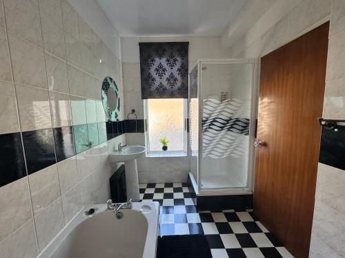 een badkamer met een bad, een douche en een wastafel bij The Holmlea in Blackpool