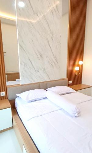 a bed with two white pillows in a room at Yasmine Homestay Rejodani in Ngaglik