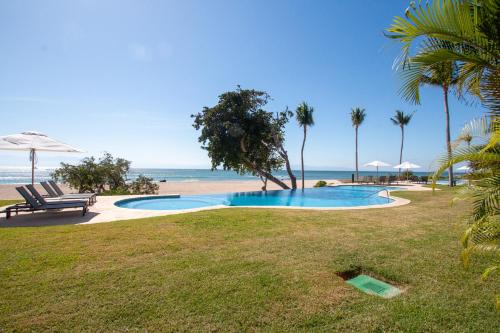 a swimming pool with a bench and the beach at Hacienda De Mita, Close to Ocean and Golf in Punta Mita