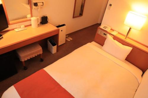 a hotel room with a desk and a bed and a desk at 青森フォレストホテル アネックス in Aomori