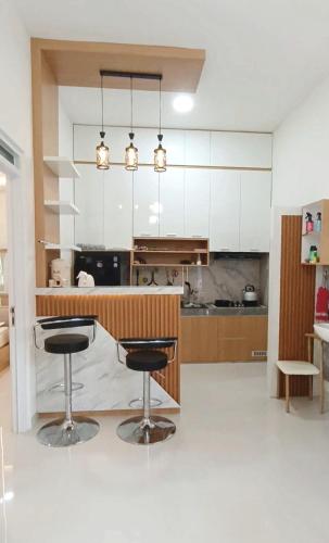 a kitchen with two bar stools and white cabinets at Yasmine Homestay Rejodani in Ngaglik