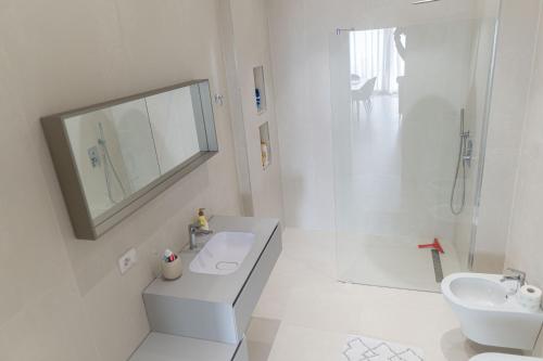 a white bathroom with a sink and a shower at Crystal Beach Radhime in Vlorë