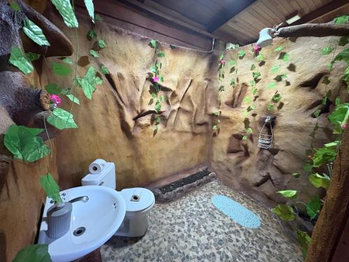 a bathroom with a toilet and a wall with plants at Bungalow con jacuzzi YeyYe in Chachagua