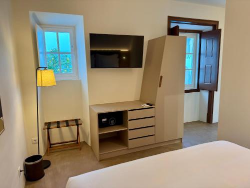 a room with a bed and a desk and a refrigerator at CICIOSO boutique hotel in Évora