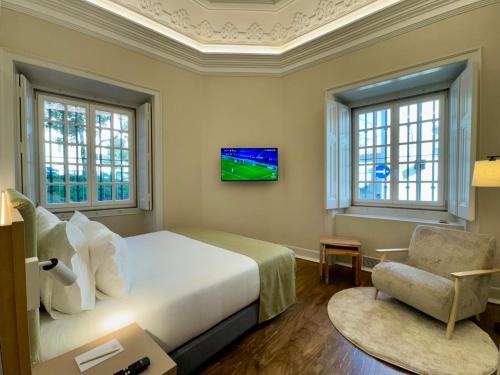 a bedroom with a bed and a tv and a chair at CICIOSO boutique hotel in Évora
