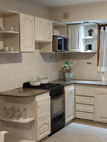 a kitchen with white cabinets and a stove at Casa cerca de la playa in Mar del Plata