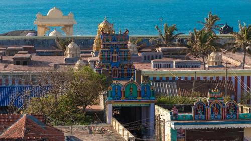a building with a tower in front of the ocean at Tamizh Nest - தமிழ்க்குடில் in Kanyakumari