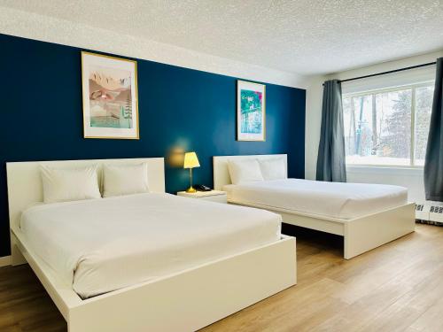 two beds in a room with blue walls at Cloud 9 Inn in Whitecourt