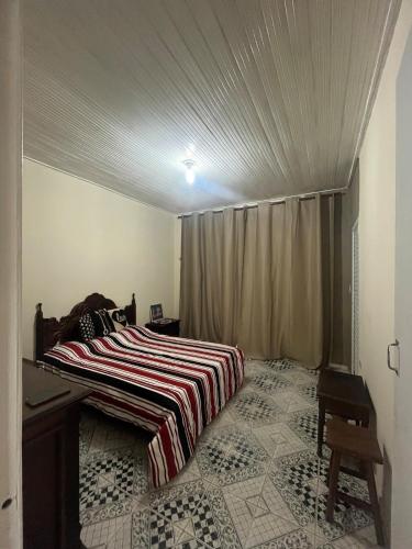a bedroom with a bed with a striped blanket on it at Apê Estação do Sorriso in Bananal