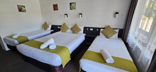 a room with three beds with towels on them at Azalea Motel in Coonabarabran