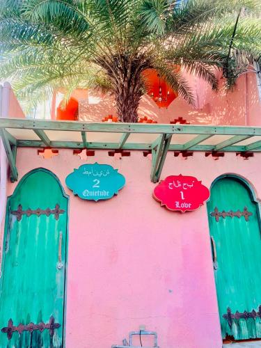 a pink building with green doors and a palm tree at A Fei Surf Inn III in Nanwan