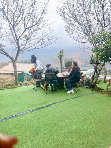 a group of people sitting at a table on the grass at Sapa Eco Hugo in Sa Pa