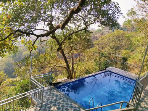 a house with a swimming pool in the trees at Sunset Valley Kerala Pool Resort - Monsoon Forest Cottage Stay in Idukki with Private Waterfalls, Natural Streams & Breathtaking Views in Pīrmed