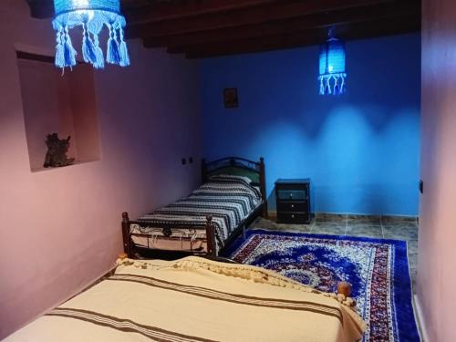 two beds in a room with blue walls at Dar Zitouna in Chefchaouene