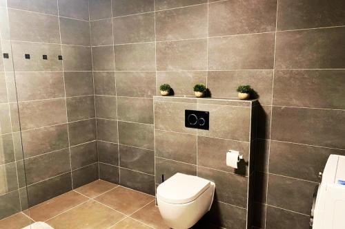a bathroom with a toilet and two plants on the wall at Cozy 120m Apartment with 3 Bedrooms and 1 Cinema in Useldange