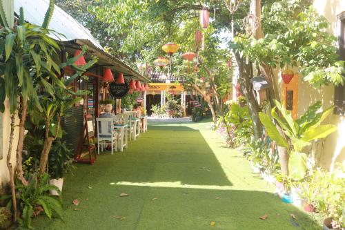 a walkway with tables and chairs in a garden at Loc Phat Hoi An Homestay in Hoi An