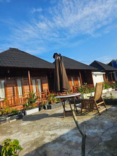 a patio with a table and an umbrella and a house at Amore Komodo in Labuan Bajo