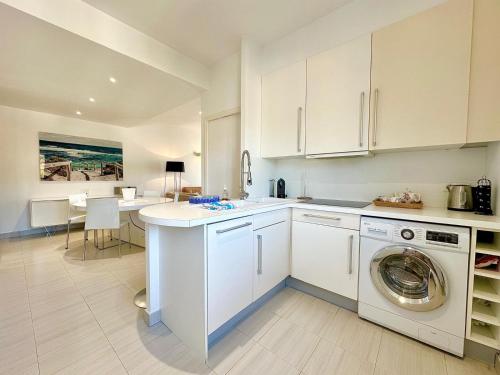 une cuisine avec des armoires blanches et une machine à laver dans l'établissement 2 Bedroom Sea View Gallia Centre Cannes parking, à Cannes