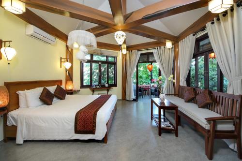 a bedroom with a bed and a couch and windows at Loc Phat Hoi An Homestay in Hoi An