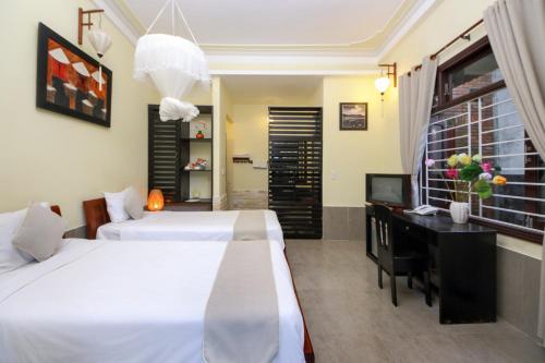 a bedroom with two beds and a desk with a computer at Loc Phat Hoi An Homestay in Hoi An
