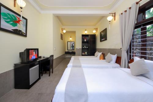 a hotel room with four beds and a television at Loc Phat Hoi An Homestay in Hoi An