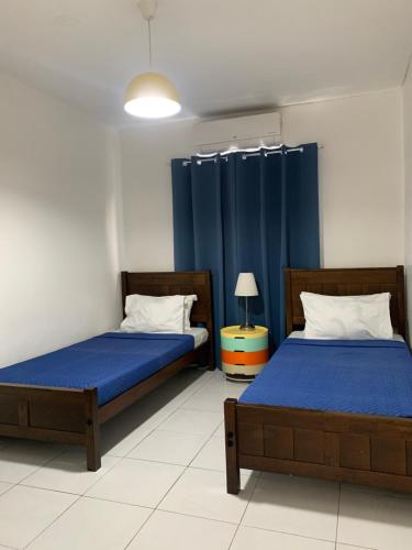 2 letti in una camera con tende blu di The Barkly House Staycation a Biñan