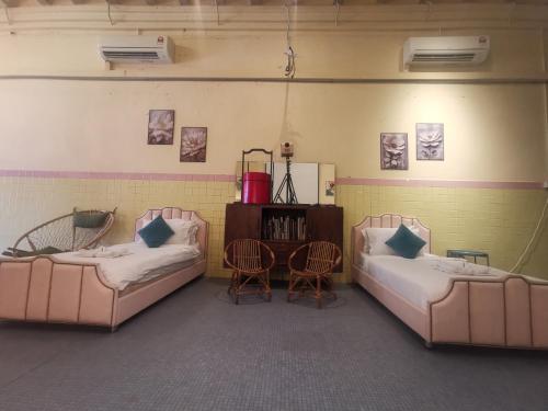 a room with two beds and a table and chairs at MacGem Heritage House at Georgetown Penang in George Town