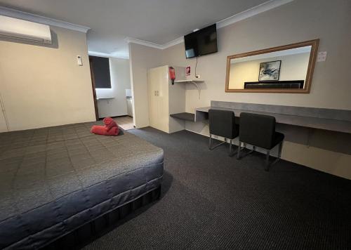 a room with a bed and two chairs and a mirror at Almond Inn Motel in Tamworth