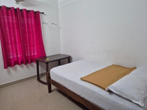 a bedroom with a bed and a table with a red curtain at Anivilla Holiday Home Kunjithanny in Anachal