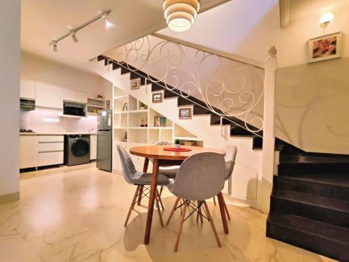 a dining room with a table and chairs and a staircase at Riviera 01, Siolim- 3BHK Villa With Pool View in Siolim