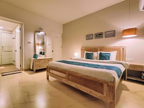 a bedroom with a large bed and a bathroom at Riviera 01, Siolim- 3BHK Villa With Pool View in Siolim