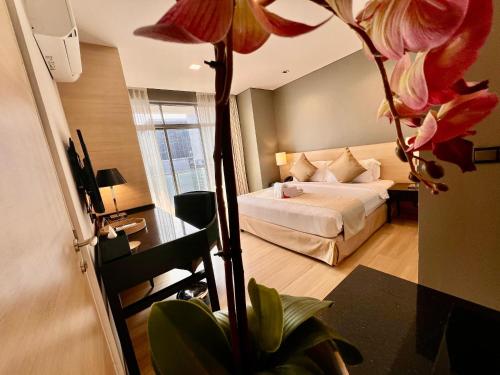 マラッカにあるASIA MELAKA HOTEL managed by The Straits Hotel & Suites 马六甲亚逸酒店のベッドと大きな花が備わるホテルルームです。