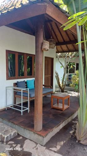 a patio of a house with a table and a bench at Si Pitung Village in Gili Air