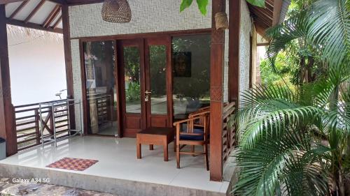 a porch of a house with a desk and a chair at Si Pitung Village in Gili Air