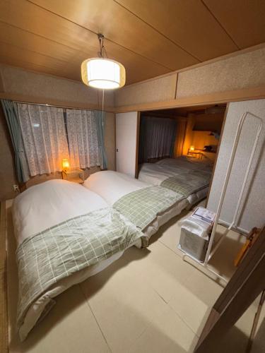 two beds in a small room with a light at シマエナガニセコ in Kutchan