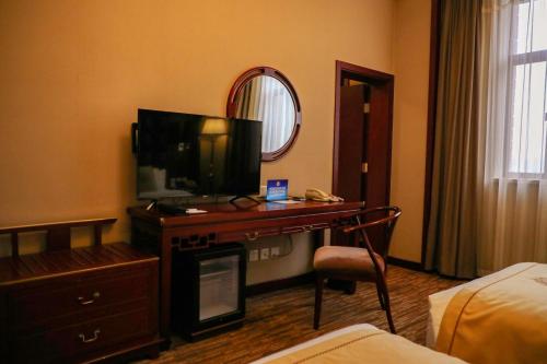 a hotel room with a desk with a television and a bed at Jianguo Qianmen Beijing in Beijing