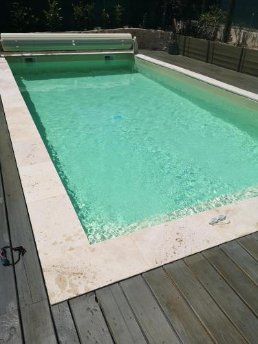 une grande piscine avec une terrasse en bois dans l'établissement Villa provençale, à LʼArbresle