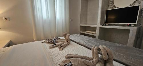 a bedroom with a bed with a television and towels at Hotel Pleasure Black Beach Perissa Santorini in Perissa