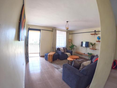 sala de estar con sofás azules y TV en Savannah Suites Gilgil, en Gilgil