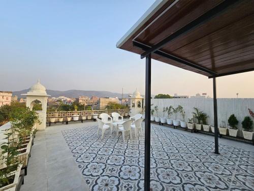 a patio with white chairs and tables on a roof at 4BHK Penthouse Near Amer Fort-5 mins to Jal Mahal in Jaipur