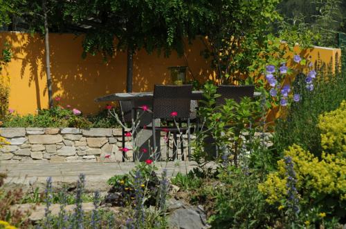 two chairs and a table in a garden with flowers at Sulamith Ferienhaus mit Garten in Sankt Kathrein am Offenegg