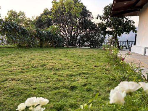 a yard with white flowers in the grass at The Green Gate Resort Mulshi in Pune