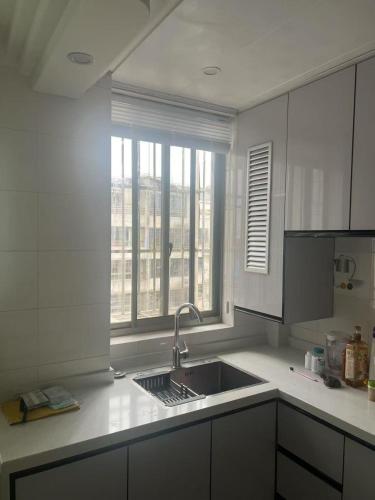 a white kitchen with a sink and a window at Huinan Accommodation, Close to Airport, Disney Resort, Wild Animal Park, Near Metrol 16 in Shanghai