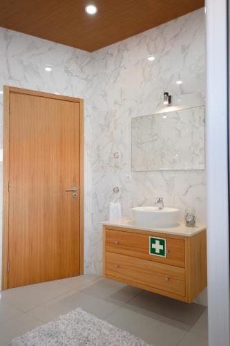 a bathroom with a sink and a wooden door at A Casa da Concha in Rabo de Peixe