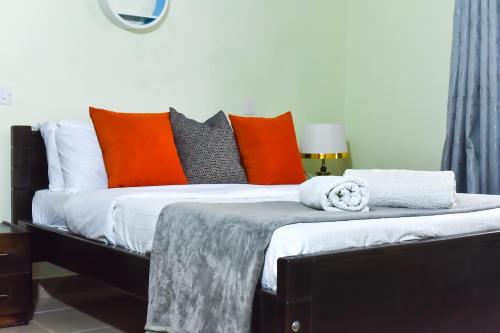 1 dormitorio con 1 cama con almohadas de color naranja y gris en Savannah Suites Gilgil, en Gilgil