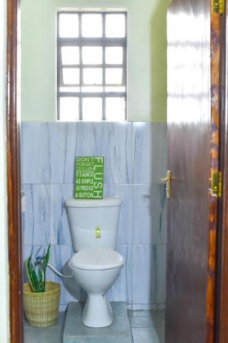 a bathroom with a toilet and a sign on the wall at Savannah Suites Gilgil in Gilgil