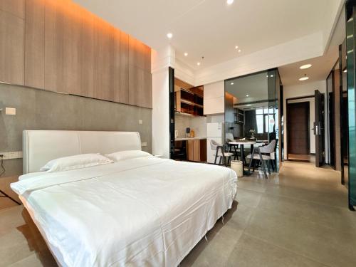 a bedroom with a large white bed and a dining room at Zhongshan Perth Hotel Apartment - Shiqi Wanxianghui Branch in Zhongshan
