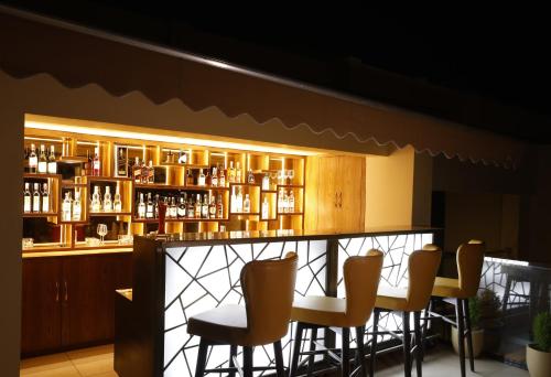 a bar with chairs and a shelf of bottles at Regenta Dehradun by Royal Orchid Hotels Limited in Dehradun